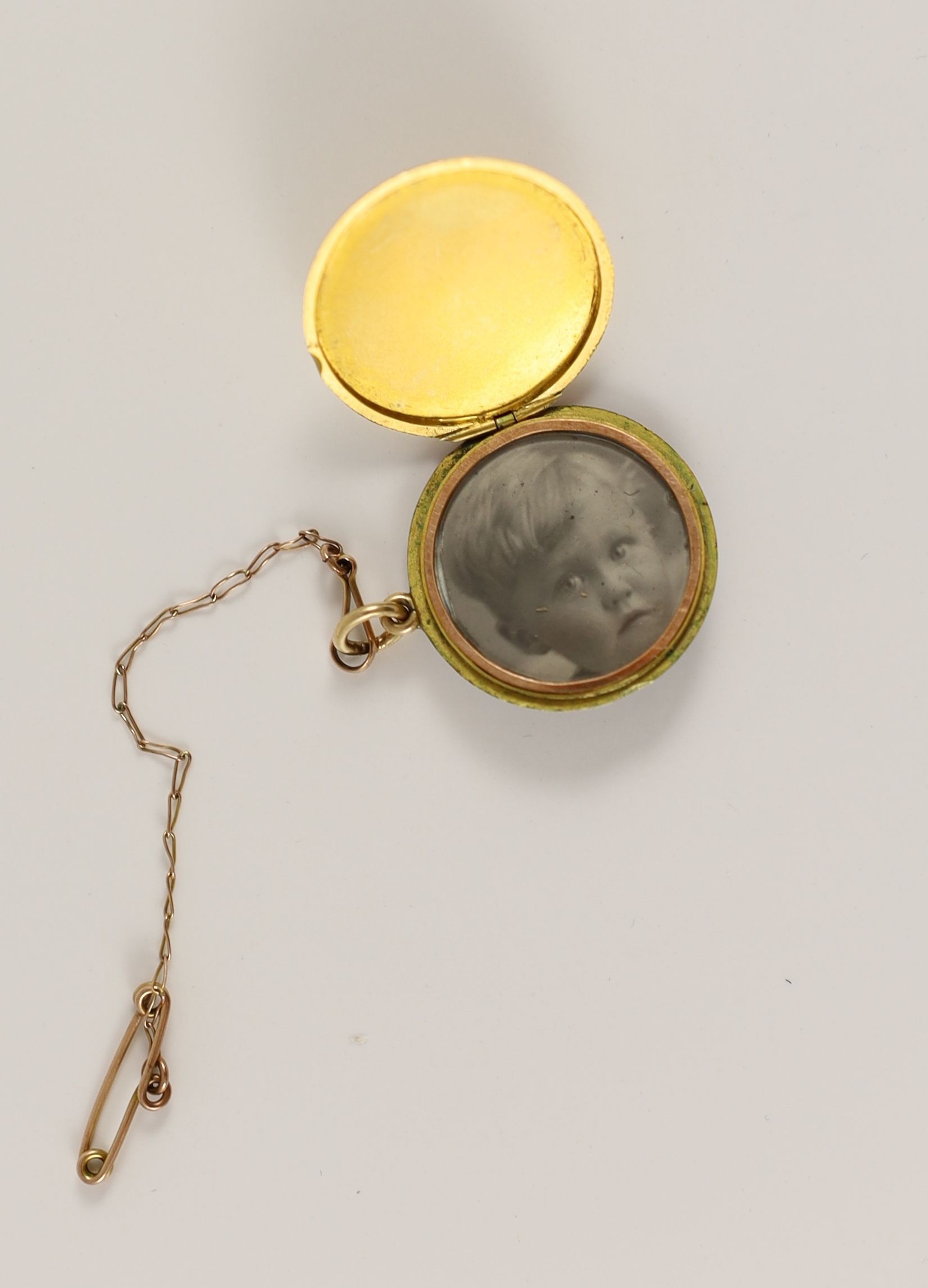 An Edwardian engine turned gold, blue guilloche enamel with gilded scrolls and diamond set circular pendant locket